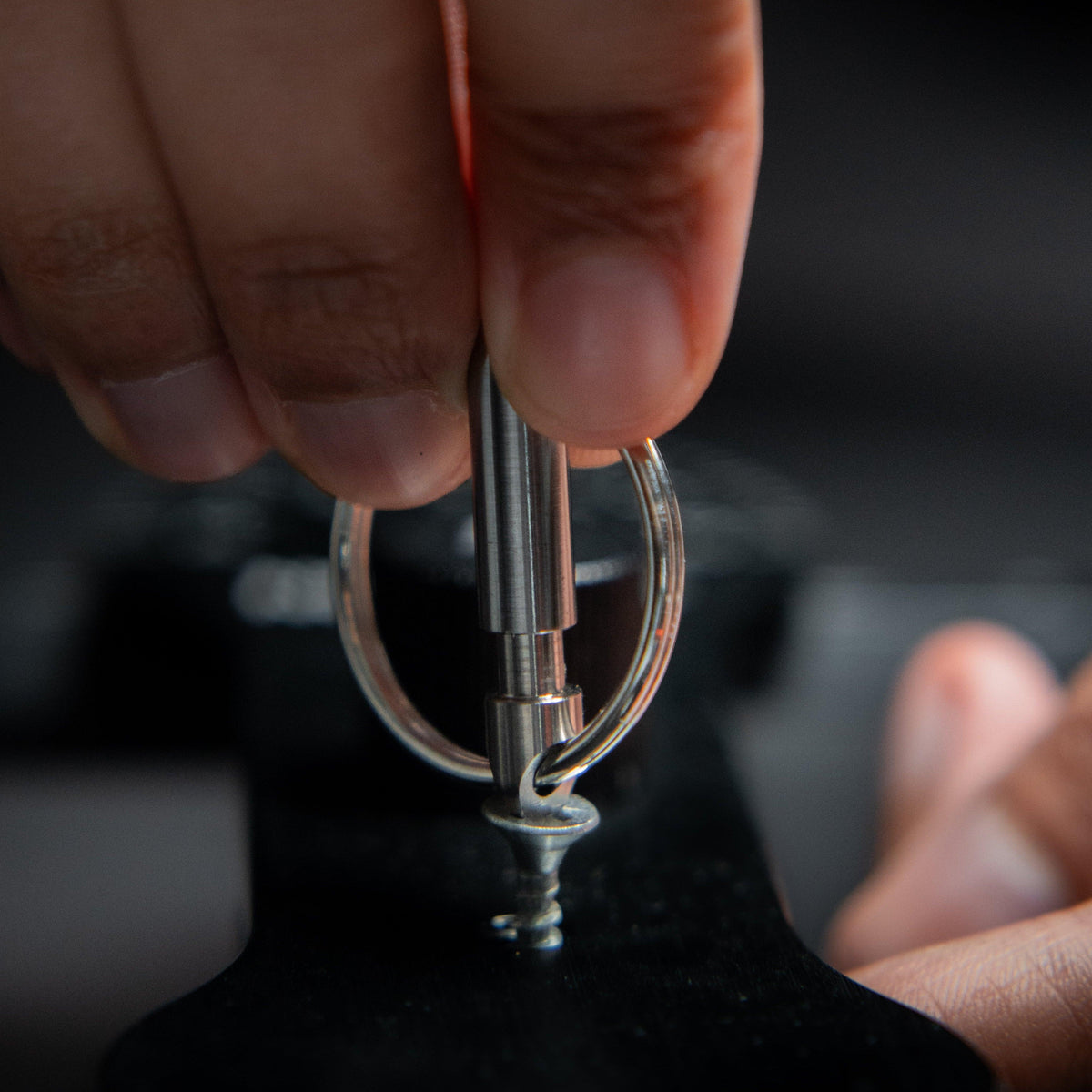 Hand using compact keychain screwdriver tool on a screw, everyday carry accessory by Gear Carry