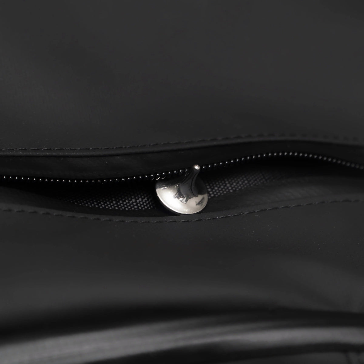 Close-up of black Gear Carry bag with metal zipper pull and durable stitching