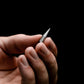 Hand holding a compact metal everyday carry tool against a black background