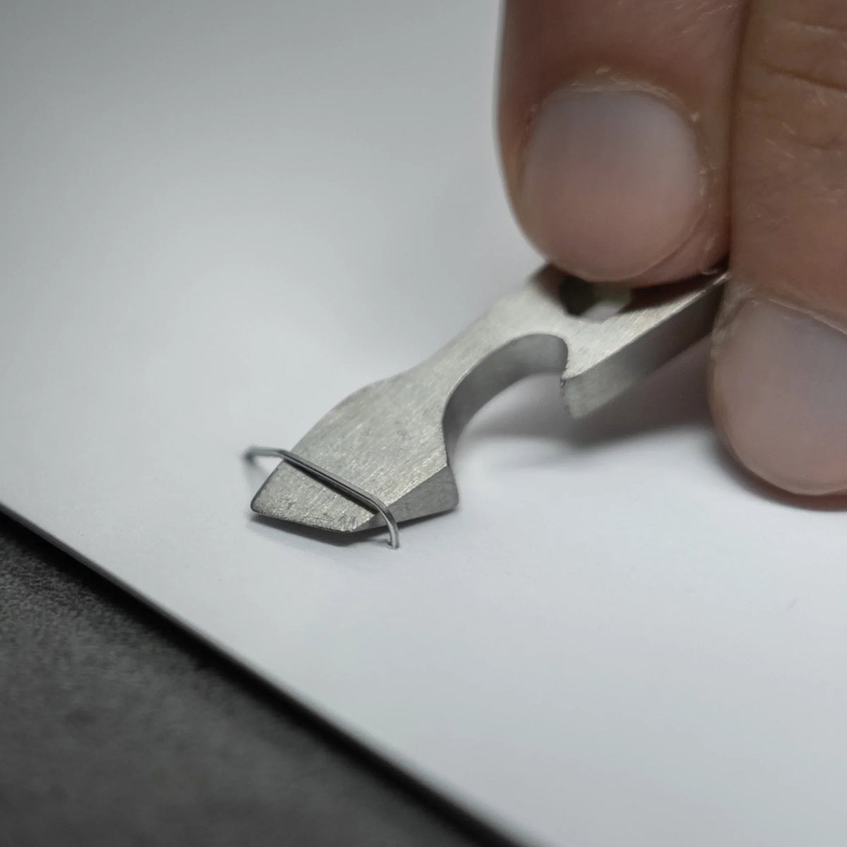 Compact titanium multitool staple remover on white paper, Gear Carry everyday accessory
