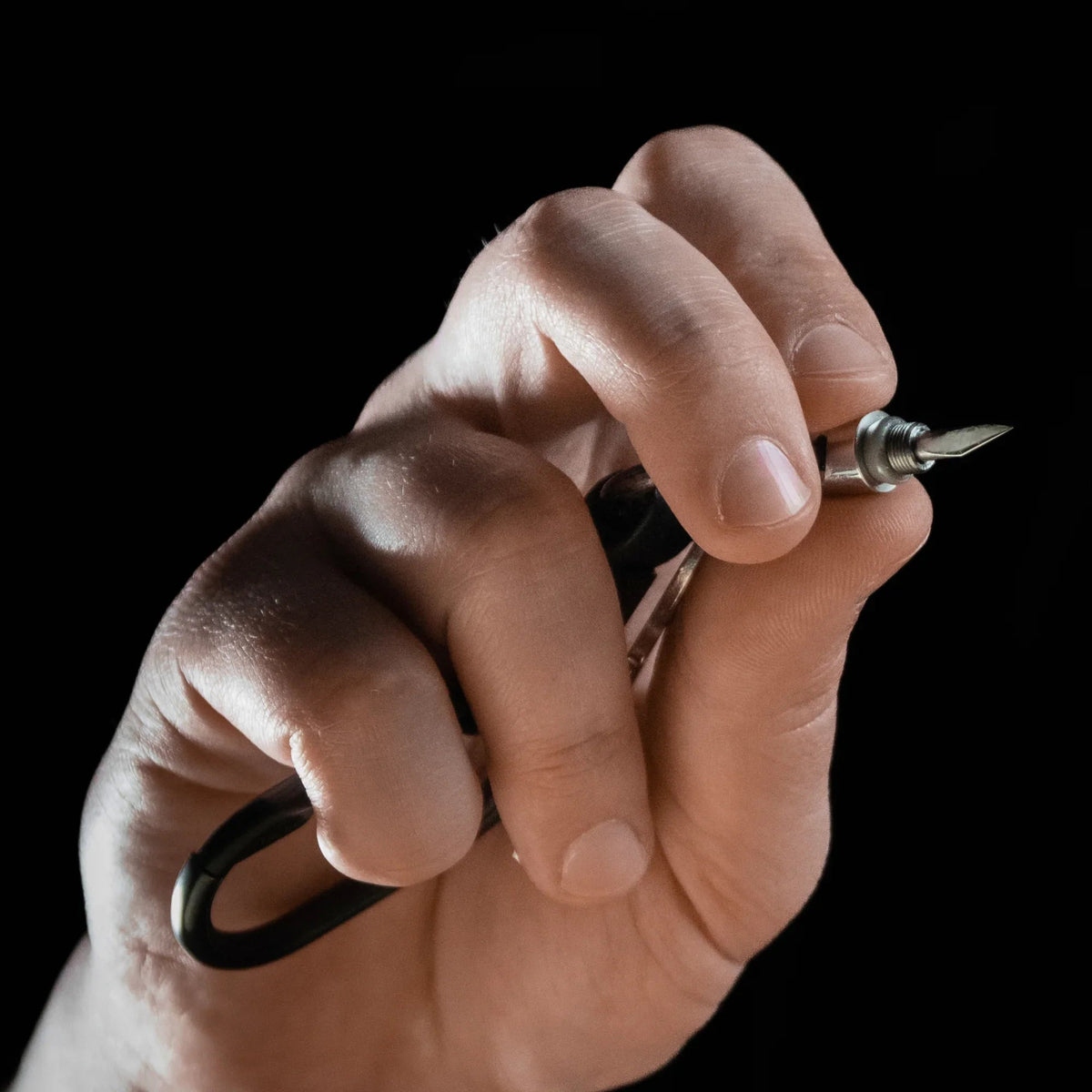 Hand holding compact utility tool with black carabiner, Gear Carry everyday essentials
